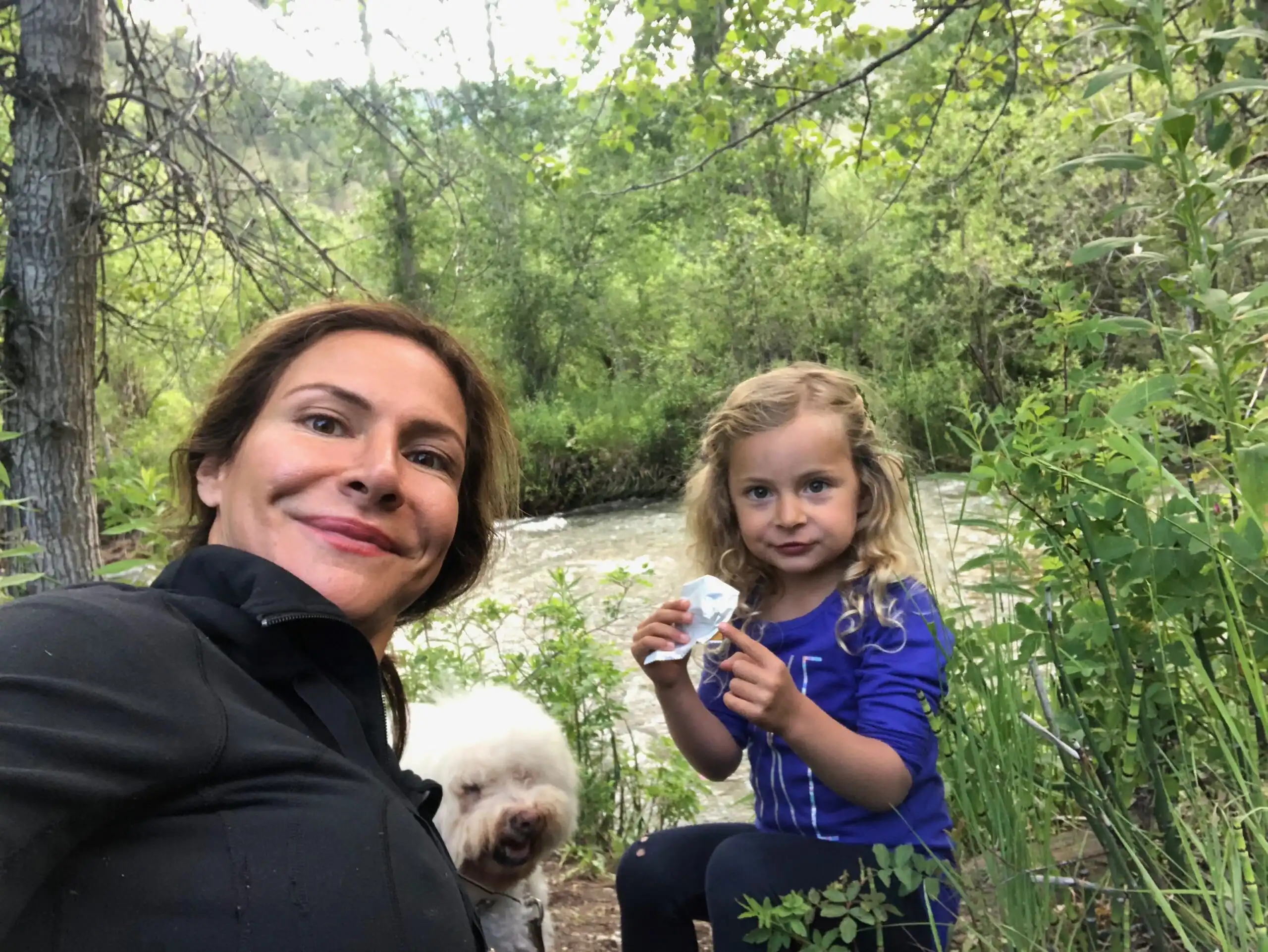 A woman and a little girl taking a selfie in the woods.